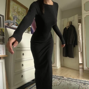 Svart långklänning med öppen rygg detalj - Säljer denna otroligt enkla men också snygga klänning. Passar till vardagen men även festligare. Jag är 165 och den går rakt ned till fötterna så verkligen långklänning. 