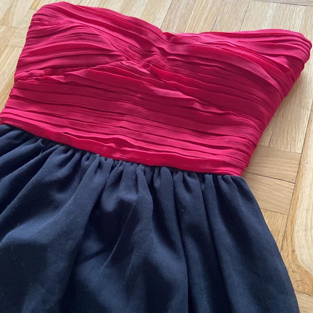 En festklänning som aldrig är använd en gång. Röd top med svart kjol, man behöver ingen bh. Kjolen är två lager. . Klänningar.