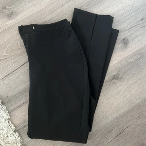 Kostymbyxor - Svarta kostymbyxor från nakd med slits nertill. Storlek 38