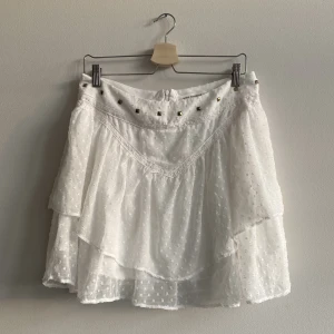 Volang Kjol  - Vit sommrig volangkjol från Sofie Schnoor i storlek M, passar även S💘 Många snygga detaljer så som nitar och spets. Perfekt till sommaren! Dragkedja i bak, fint skick! Köparen står för frakten, bara att höra av sig med frågor eller för fler bilder! 💘