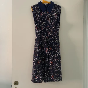 Klänning svamp-motiv - En ärmlös klänning med svampmotiv och skjortkrage. Öppnas med blixtlås i ryggen. Har skärp som knyts runt midjan. Är för liten för mig nu så säljer gärna. 