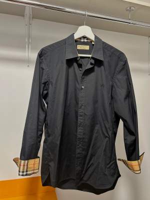 Säljer en jättefin Burberry skjorta i storlek M. Skjortan är i den nya modellen i svart. Skjortan är endast använd 1 gång och köpt på NK i Gbg.