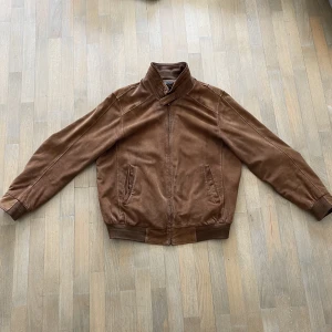 Vintage Mockajacka med skönpassform - OK skick, därav priset. Knappen längst uppe vid dragkedjan är borta, har även en liten skada på baksidan som man ser på andra bilden. Allt annat på jackan är som det ska. Najs fade och passform annars, skön fit. 🙌