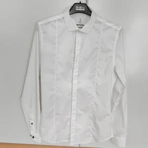 Skjorta - Vit skjorta med svarta knappar. Slim fit, bra i storleken.