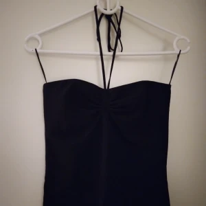 Svart halterneck topp från Gina Tricot, Strlk S-M. Nyskick. - Svart halterneck topp med knytband i nacken, från Gina Tricot, Strlk S-M. (Medium men är mer som Small i storleken enligt mig.) Bomull. Nyskick/felfri.
