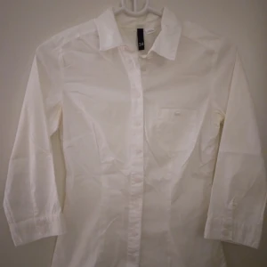 Vit skjorta / blus för kvinnor. Bomull. Strlk: 34 / XS. Felfri. - Vit skjorta / blus för kvinnor. Bomull. Strlk: 34 / XS. Säljer även en likadan fast helt ny, svart, i samma storlek.