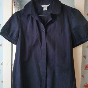 En svart kortärmad skjorta från Kumikyoku i storlek 2 = EU 34