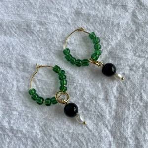 Handgjorda örhängen - Handgjorda örhängen i nickelfri mässing med glaspärlor och sötvattenpärlor. Ringens diameter är 2,5 cm  Frakt: 15 kr