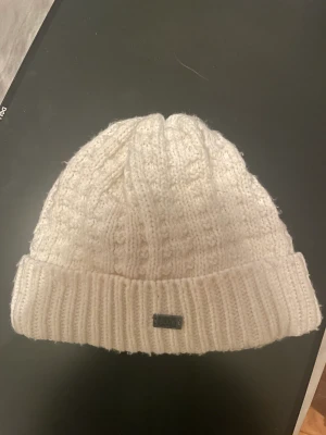vit stickad mössa från Bula - Nypris: 300kr. Den är i bra skick. Knappt använd. Perfekt nu inför vintern. Den är väldigt värmande och snygg med dess stickade mönster, Vit mössa från Bula, onesize