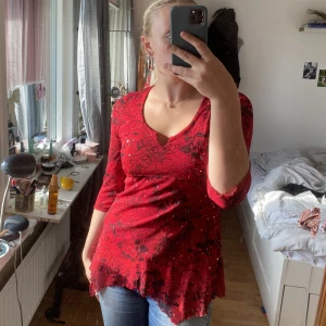 Röd topp - Jätte snygg röd topp med mönster och paljetter. Köpt second hand men i okej skick har ett litet hål under ena bröstet skriv för bättre bild. 