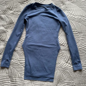 Blå långärmad med slits  - Helt oanvänd och i super bra material. Den har höga slitsar och har hål för timmarna. 