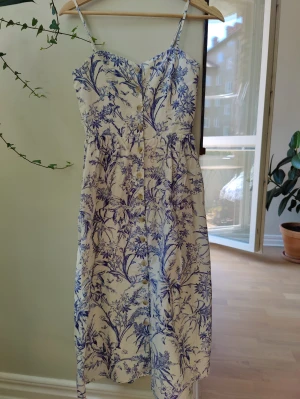 HM Blommig klänning 34 - Blommig klänning i linmix. Några få låda trådar kring knapparna annars mkt bra skick. 