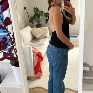 Topp  - Svart topp som man knyter i nacken, bar rygg. ganska stor i storleken, känns som en medium 