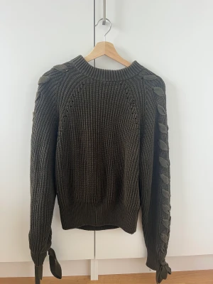 Stickad tröja  - Mörkgrön stickad tröja från HM i USA. Knytdetaljer på ärmarna.