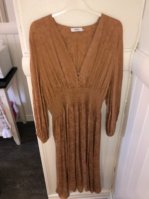 Stylein klänning - Säljer denna super fina Beiga/bruna klänningen från Stylein! Säljer pga passar inte i färgen. Endast använd 2 gånger! Nypris ca 3500 kr.