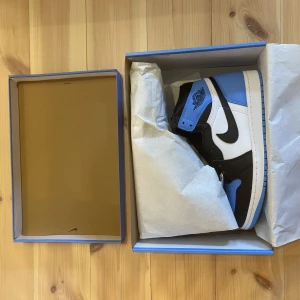 Air Jordan 1 retro high OG UNC toe - Storlek EU:43, US:9,5 Fräsha skor som köptes från Nike Snkrs appen vid släppet av skorna. Skorna är helt oanvändna och kommer med extra skosnören i blå och skolåda (lådan är i utmärkt skick).  Skorna kommer även med digitalt kvitto och beställningsbevis. 