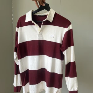 Acne Rugbytröja - Rugby tröja från Acne studios. Välanvänd med tecken av användning: mindre fläck på framsidan samt slitningar vid knapphålen.