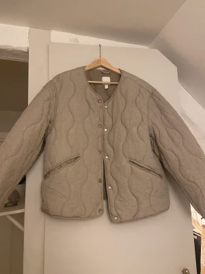 Dunjacka  - Quiltad ”dun” jacka från H&M i en ljus grön/grå färg. Tror att jag köpte den förra året men är endast använd vid ett fåtal tillfällen. 