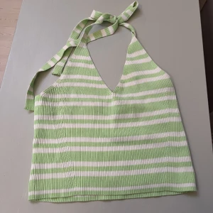 Halternecktopp Stradivarius  - Grön och vit-randig halternecktopp från Stradivarius. Den gröna färgen är mer åt ett neon-håll i verkligheten. I fint begagnat skick. Du knyter själv banden runt halsen och kan därför reglera hur du vill att den ska sitta.