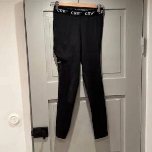 Vinter-ridtights - Svarta ridtights från CRW med fleece-insida som är mycket sköna att rida i på hösten/vintern. Dottern har haft dem en säsong, nästan som nya, storlek 152-164. Halvskodda med ”gummiprickar” som ger bra fäste mot sadeln. 
