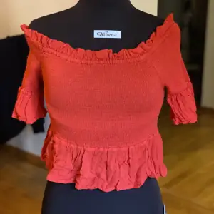 Röd topp som är croppad med volangdetaljer. Trekvartsärmar. Off-shoulder. Storlek 42, från Gina Tricot. Använd men i gott skick!