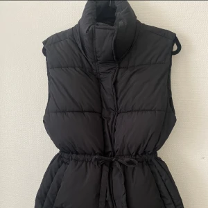 Svart väst i nyskick - Svart väst med knyte i midjan. Endast använd i någon timme, så skicket är som nytt. Säljes då jag har en liknande. Storlek XS men passar S också. Nypris 600kr 