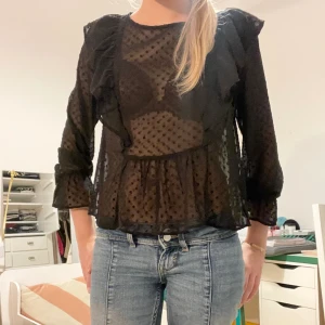 Svart prickig blus - Sött svart prickig blus lite genomskinlig med volanger på axlarna