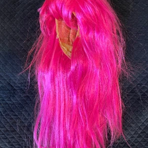 Rosa peruk - En neonrosa peruk💕Använd en gång. Lite trasslig på bilden, men gör självklart iordning den innan jag skickar den 😊 (frakt ingår ej)