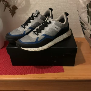 Hugo Boss skor. - Säljer dessa skor eftersom dom har inte kommit till användning på ett tag, har använt dom ett par gånger som löparskor, väldigt bra och bekväma skor att springa och träna med dessutom det som gör dom coola är att den silvriga ytan lyser i mörkret.