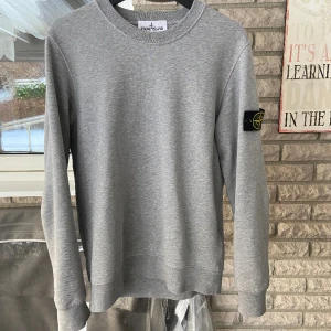 Stone Island Sweatshirt  - Grå sweatshirt från Stone Island köpt på plick av någon som inte ville ha den. (Inga fläckar på tröjan, bara lite slittna sömmar)  Clg nummer och qr kod finns på bild.  Säljer för jag knappt har använt den. Ny pris ligger på runt 2800kr på NK