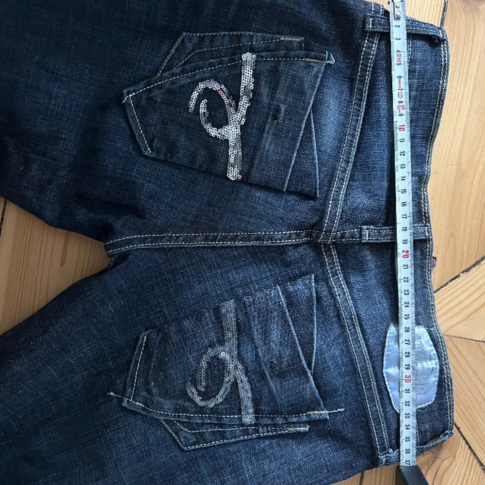 Vintage jeans! Svincoola med 2 nitar och knäppning med knappar. Bakfickor med glitterpaljetter. Långa, passar 180+. Storlek w27 L34. I vanlig storlek mellan XS-S. Jeans & Byxor.