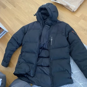 Sail racing vinterjacka - Sail racing vinterjacka i S. Håller värme bra och ser bra ut. Säljer på grund av att jag ska köpa en ny.  Skador: Det som syns på bild 3 är ett rivmärke som sedan limmats ihop, det som syns runt omkring är torkat limm.