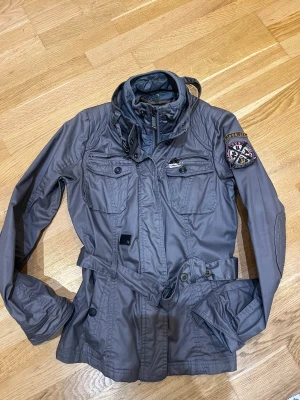 Cool höstjacka - Cool höstjackan med avtagbar fejkväst. Oljat utseende. Grå/mullvad i färgen. Liten i storlek mer som en M