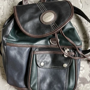 Vintage Ryggsäck / axelväska  - Min fantastiska mini ryggsäck i läder, köpt second hand för några år sedan. Låset finns inte men den går att stänga. Den har två band för att använda som ryggsäck som man även kan dra ihop med en dragkedja för att ha den över axeln. Hur cool som helst. 