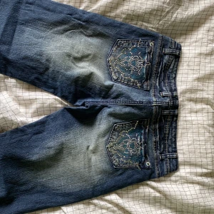 Lågmidjade jeans med fick design - Lågmidjade, nästan inte alls använda, skitsnygga med stenar som pocket design. Dom är för små så har inga bilder med dom på!