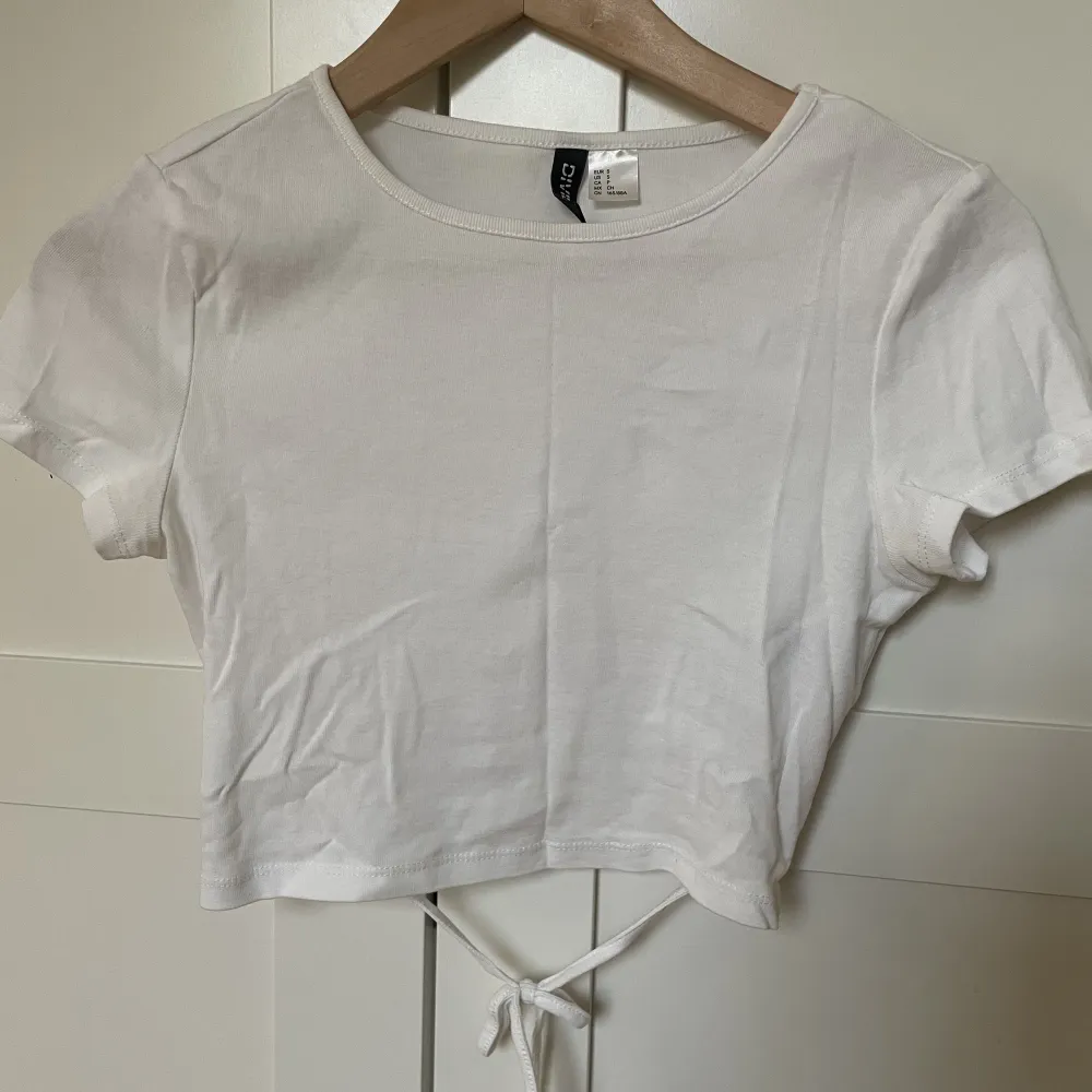 Säljer denna snygga vita t-shirten med knytning i ryggen💗endast använd en gång . Toppar.