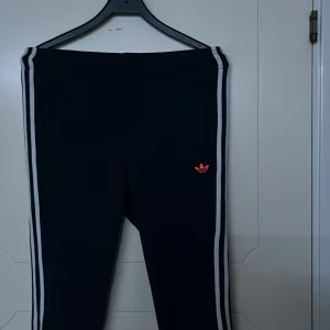 Tjock byxor  - Mörk blåa Adidasbyxor med vita linjer och en mörk röd och orange under del. Byxorna är i bra skick och bara använts en eller två gånger. 