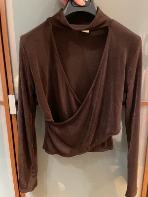 Chiquelle brun topp v-ringad omlott medium ny - Snygg topp i brunt lite skimrande stetchigt tyg. Kort modell. Storlek M. Aldrig använd. 