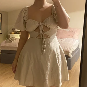 Miniklänning  - miniklänning med knytningar framtill i beige färg o linne material i storlek s passar nog 36