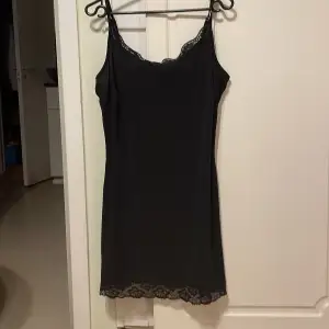 En svart silkes klänning med spets. Den har använts några gånger men är som ny. Dock har jag klippt bort lappen (se bild)