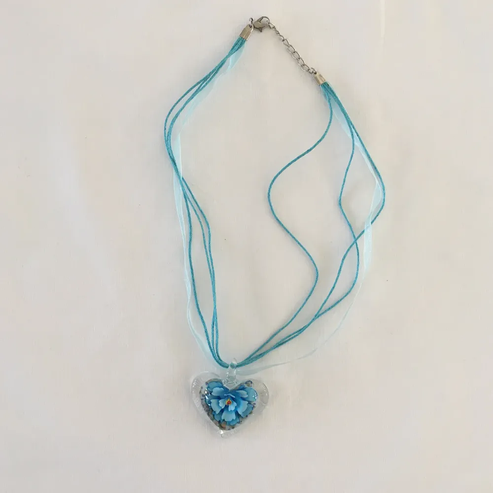 Häftigt halsband med ett stort glashjärta med en blomma i. Det är en statement piece som ger y2k. . Accessoarer.