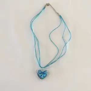 Häftigt halsband med ett stort glashjärta med en blomma i. Det är en statement piece som ger y2k. 