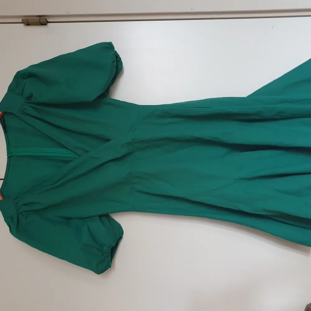 En grön klänning med puffärmar och blixtlås där bak. Den är aldrig använd. Den var inte min stil. . Klänningar.