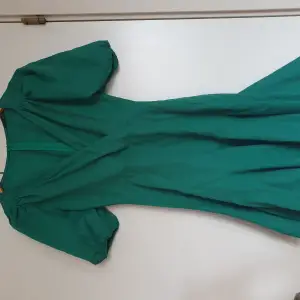 En grön klänning med puffärmar och blixtlås där bak. Den är aldrig använd. Den var inte min stil. 