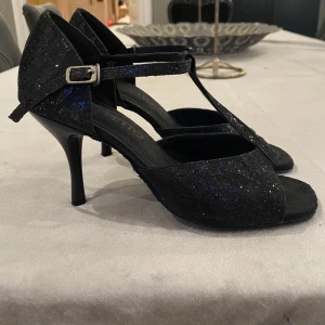 Svarta glittriga klackskor | Geppetto - Ett jättefint par svarta glittriga klackskor från Geppetto. De är i använt skick, för bilder på det lilla slitage som finns, skriv privat! Slitaget är inget man ser när man har på dem dock!🥰 Skriv privat för mer info och bilder.