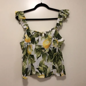 Croppat linne - Kort linne med liten volang på axelbandet. Citroner som motiv. Oanvänd med prislapp kvar. 