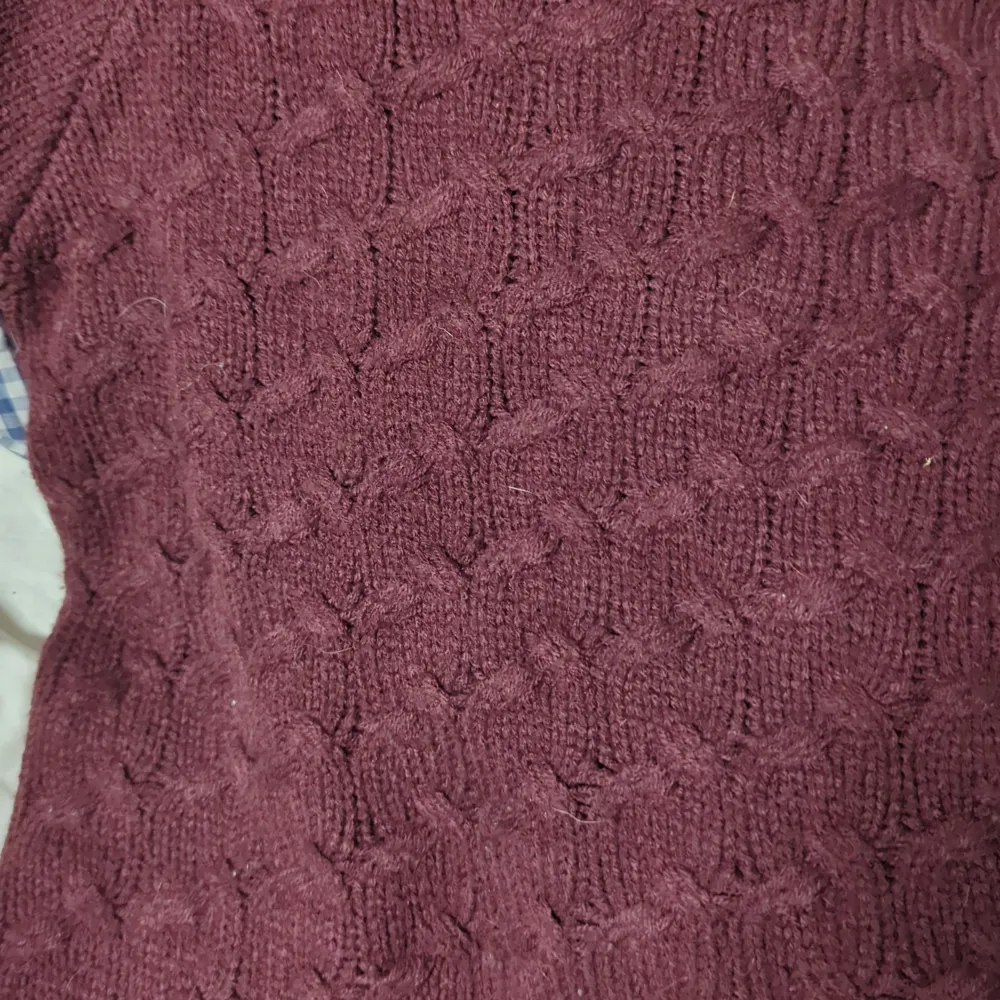 En vinröd tröja som jag aldrig använt. Den har en liten slits på båda sidor och sticks inte.. Stickat.