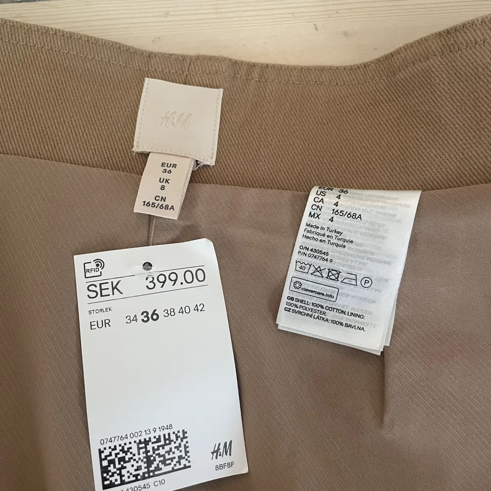 Fin beige/brun kjol med knapp och bälte från HM Helt oanvänd med prislappen kvar. Storlek: 36 100% bomull . Kjolar.
