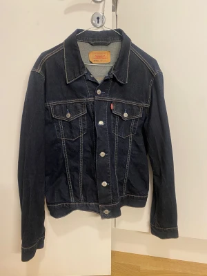 Vintage Levis Jeansjacka - Säljer en oanvänd vintage Levi’s jeansjacka på grund av att jag har en liknande. Jackans originalpris var 1399kr, men säljer nu för endast 350kr. På taggen står det att jackan är i storleken L, men skulle säga att den är mer utav en M eller en oversize S.