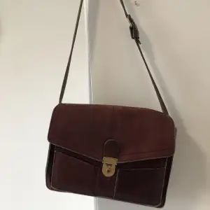 Jättefin läderväska i portföljform som jag tyvärr inte för använding av då min dator inte får plats i den, skulle beskriva väskan som mer av en handväska! Köpt vintage, är i perfekt skick. Syns inte så bra på bilden men den är vinröd med gulddetaljer!